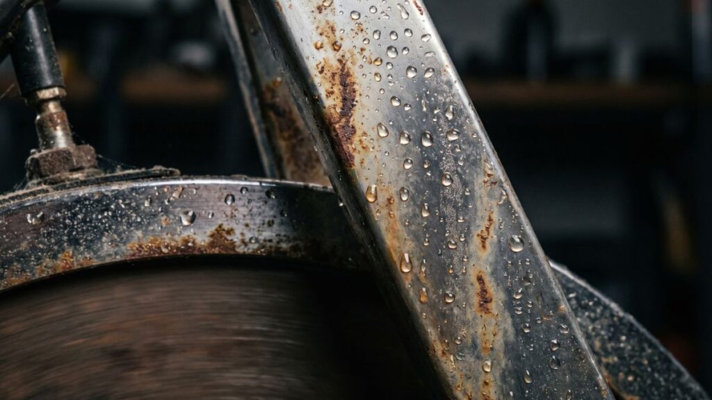 Detalhe de gotas de suor sobre a estrutura de metal de uma bicicleta ergométrica, ilustrando o perigo da corrosão nas peças.