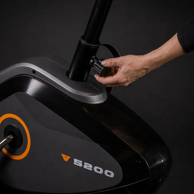 Bicicleta ergométrica vertical Evox Fitness V5200 magnética na cor preta em vista lateral.