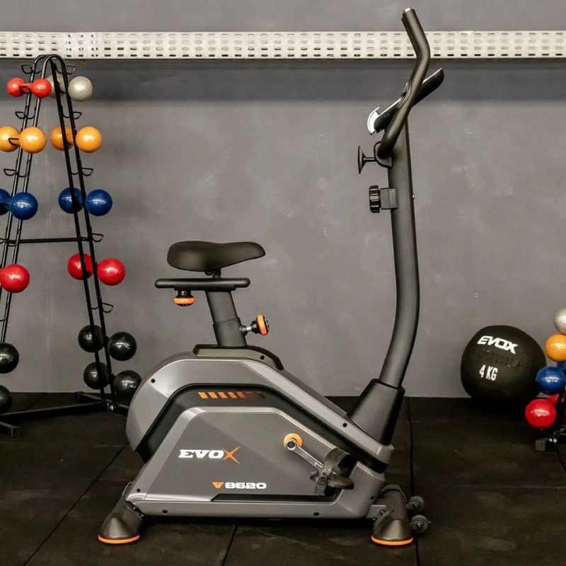 Bicicleta Ergométrica Vertical Evox Fitness V8620 em ângulo frontal exibindo painel e estrutura grafite e preta