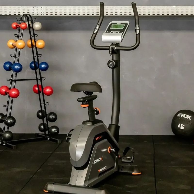 Bicicleta Ergométrica Vertical Evox Fitness V8620 em ângulo frontal exibindo painel e estrutura grafite e preta
