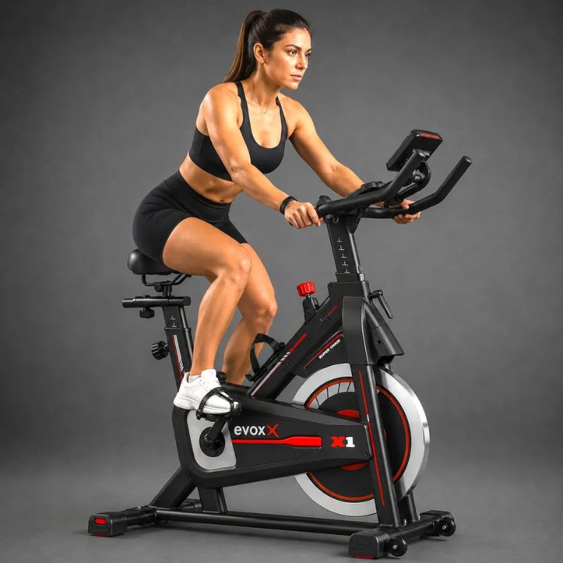Bicicleta Spinning Evox X1 preta e vermelha vista lateral completa.