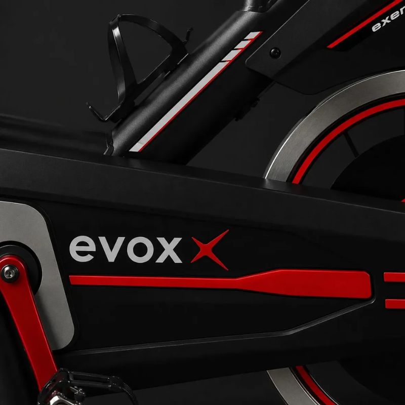 Bicicleta Spinning Evox X1 preta e vermelha vista lateral completa.