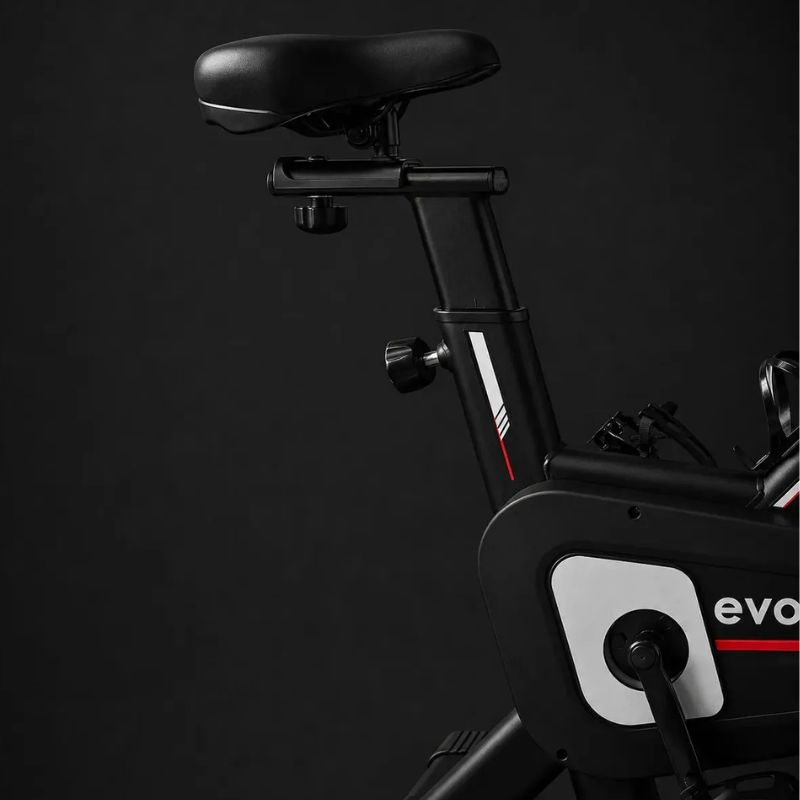 Bicicleta Spinning Evox X1 preta e vermelha vista lateral completa.