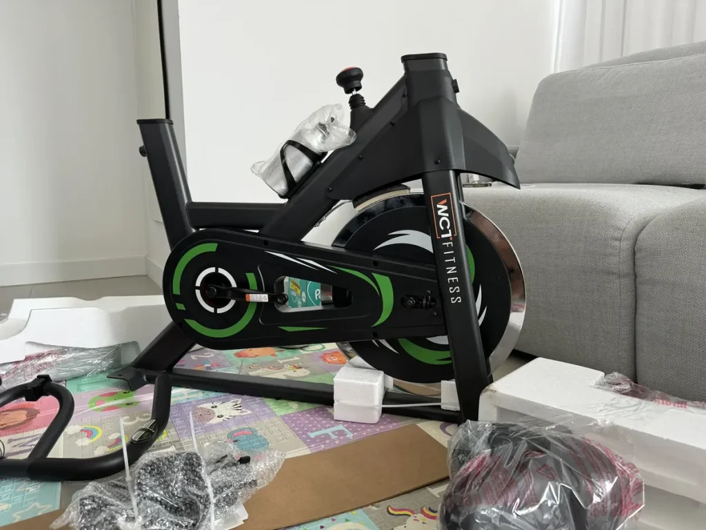 Detalhe em close-up do volante de inércia cromado de 20kg com o sistema de resistência da bicicleta WCT Fitness