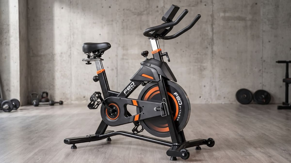 Bicicleta Spinning Yosuda FED Magnética 23kg vista lateral destacando estrutura preta e laranja