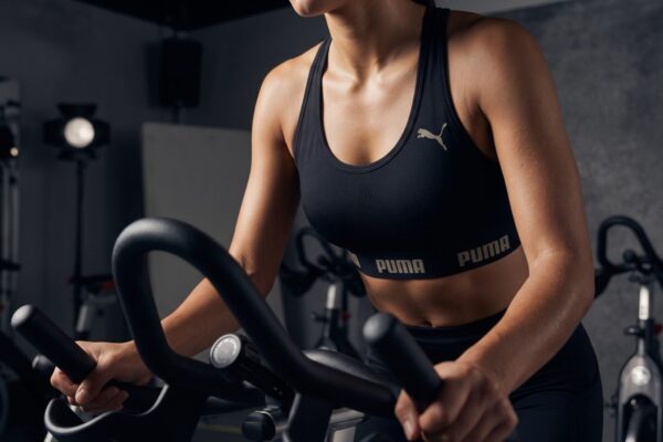 Top Puma Academia Nadador preto vestido em modelo durante treino de spinning